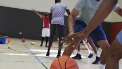 Diverse-male-basketball-players-passing-ball-and-blocking-during-game-at-indoor-court,-slow-motion