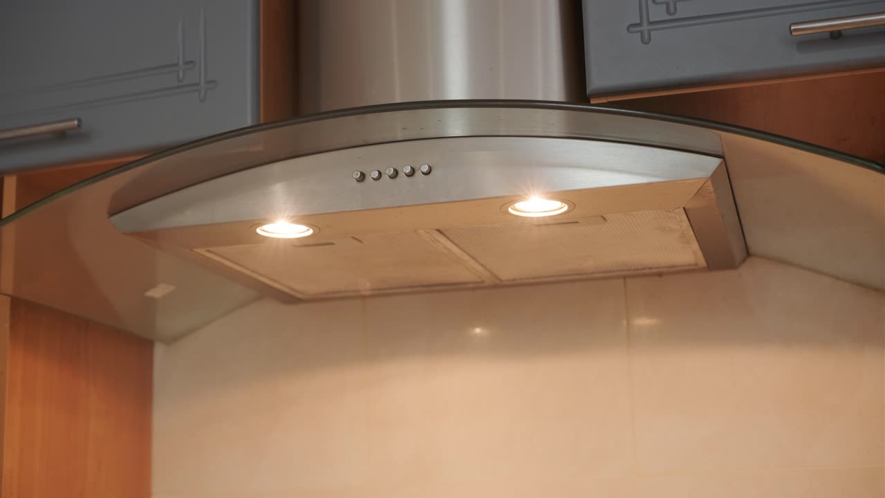 Modern Stainless Steel Range Hood with Lights On in Kitchen