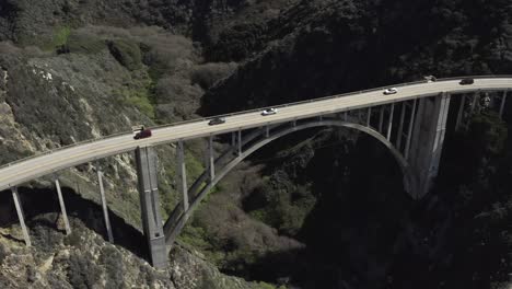 aerial pan down, bixby canyon bridge, cars on road, big sur coast, california