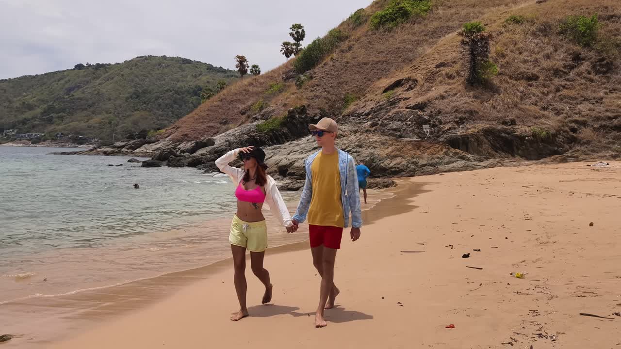 Una pareja caminando por una playa tropical.