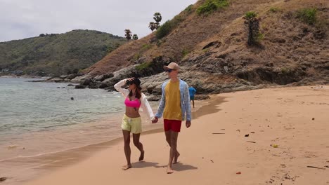 una pareja caminando por una playa tropical.