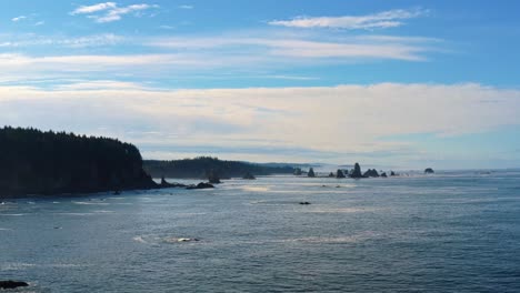 stunning aerial drone trucking left shot of the gorgeous third beach in forks, washington with large rock formations, cliffs, small waves and sea foam on a warm sunny summer morning