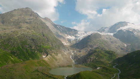 Filmische-Luftaufnahme-Des-Steinsees-Mit-Der-Malerischen-Landschaft-Des-Sustenpasses-Im-Hintergrund