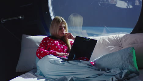 mujer trabajando en una computadora portátil en una cama de la estación espacial