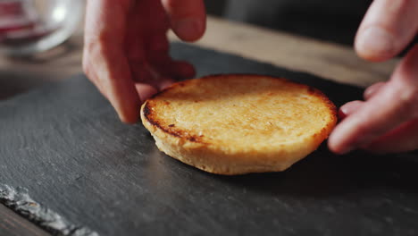 poniendo la mitad tostada del pan de hamburguesa en la mesa