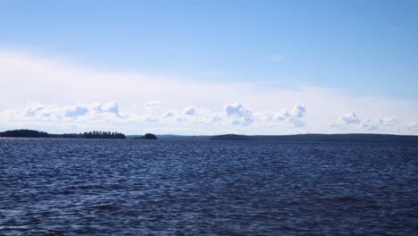 芬蘭一座巨大的湖泊的水流流動,白雲在遠處滑過一些植被