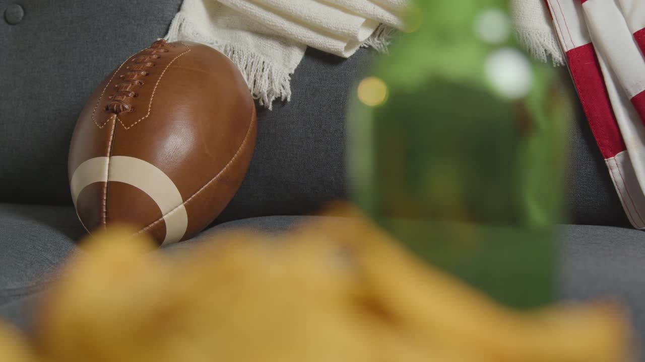 tv에서 미식축구 경기를 시청하는 사람의 집 라운지에서 음료수 스낵과 공 1