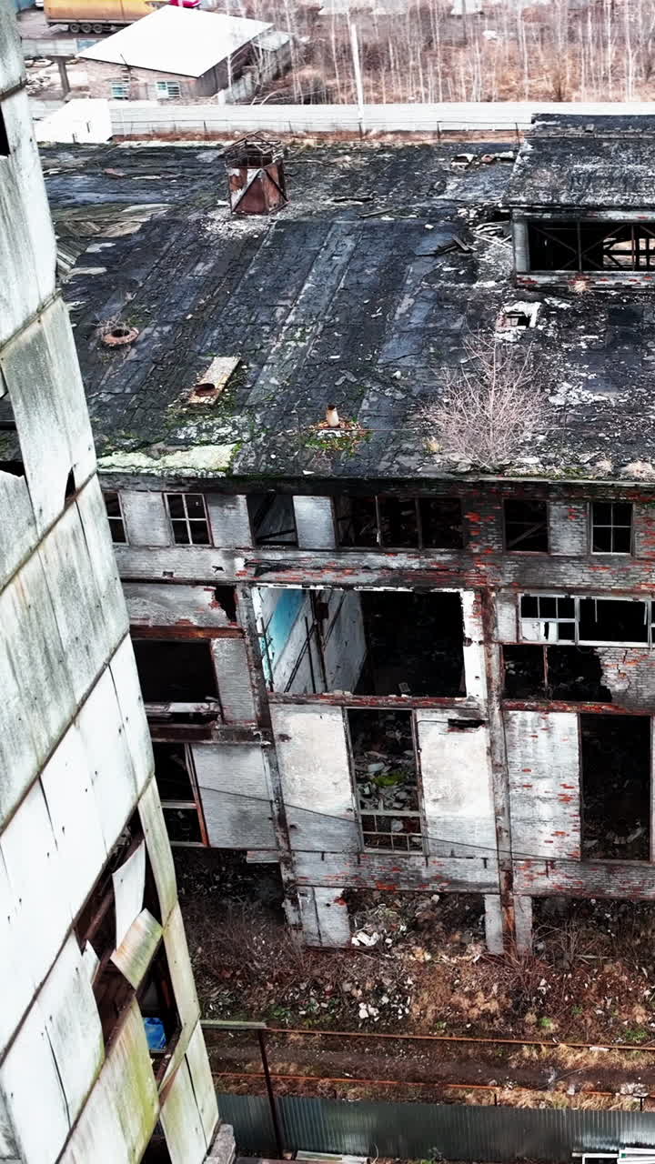 Deserted and solitary industrial zone of a plant destroyed with time. Abandoned territory dangerous for visiting. View from above. Vertical video