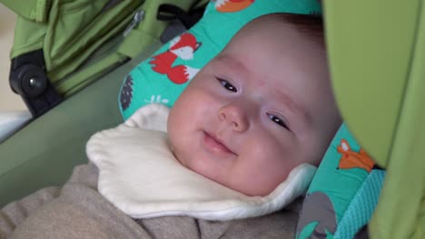 adorable baby girl smiling to the camera when lying in stroller daytime