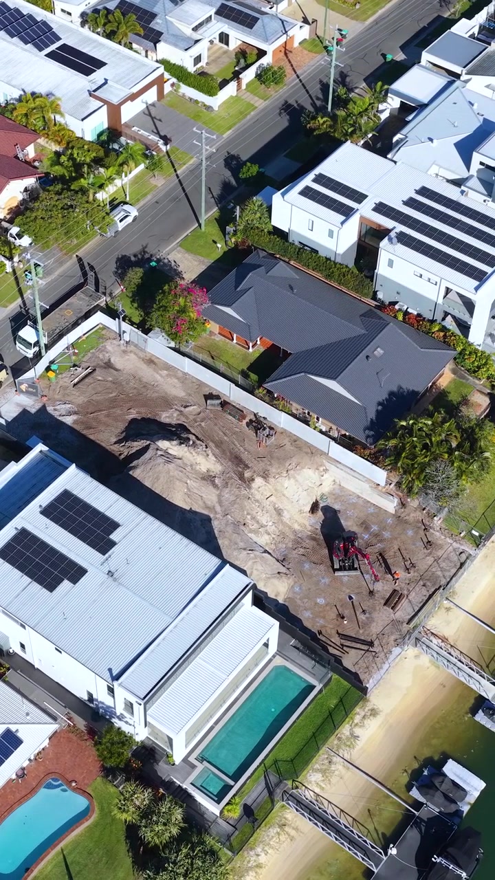 High-angle drone shot of luxury home construction and neighborhood in Broadbeach Waters, Australia.