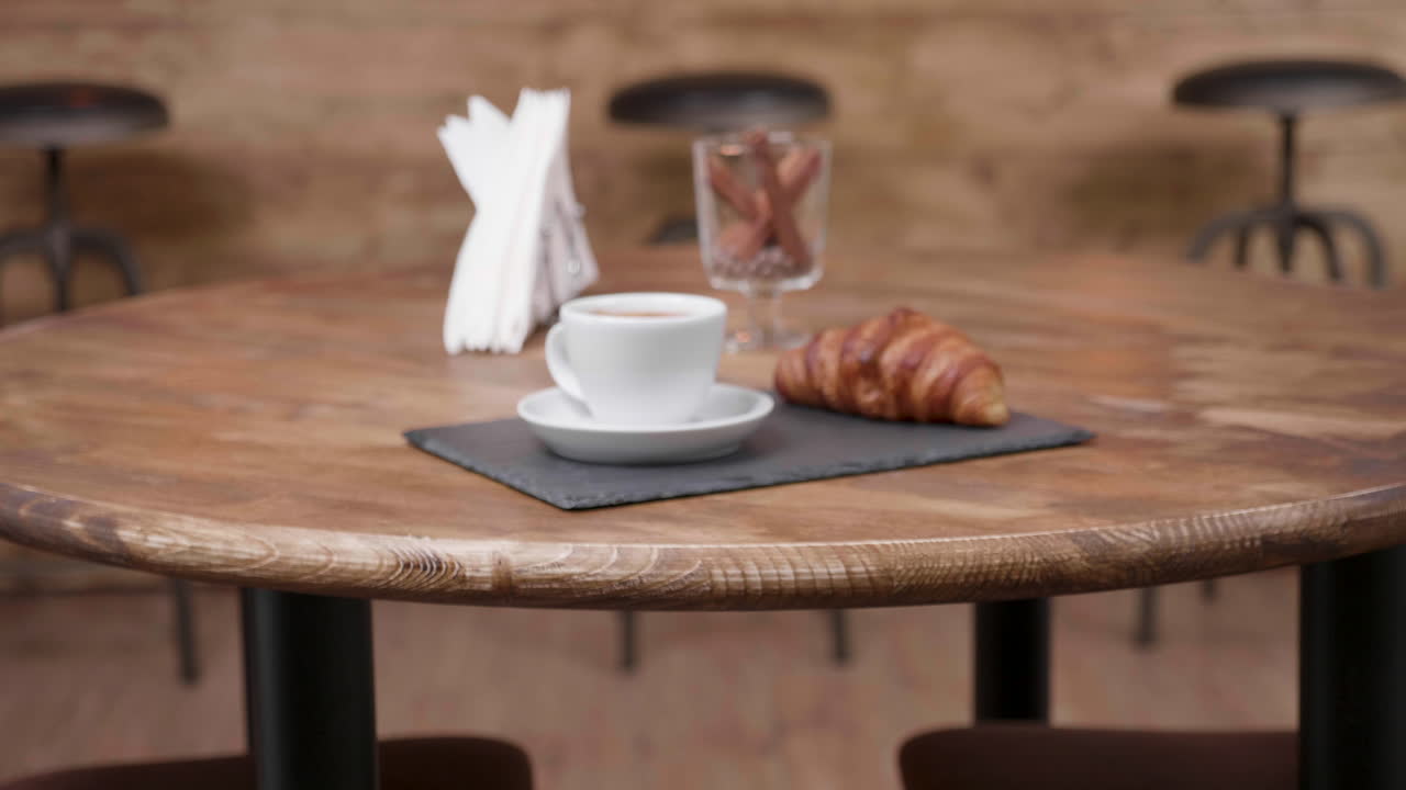 Coffee and croissant on a wooden table in a cafe