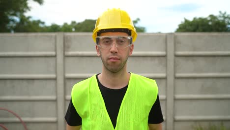 a construction worker dons a yellow hard hat along with standard safety glasses - medium close up