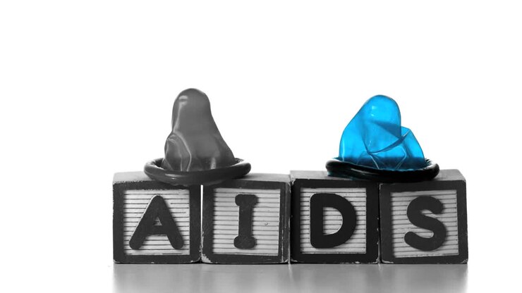 Preservativi che cadono su blocchi che formano la parola AIDS
