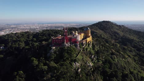 dron volando cerca del histórico castillo del palacio pena que se encuentra en la cima de una colina en las montañas de sintra sobre la ciudad de sintra, portugal