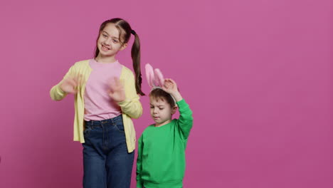 Joyful-little-kids-waving-in-front-of-camera-during-easter-holiday