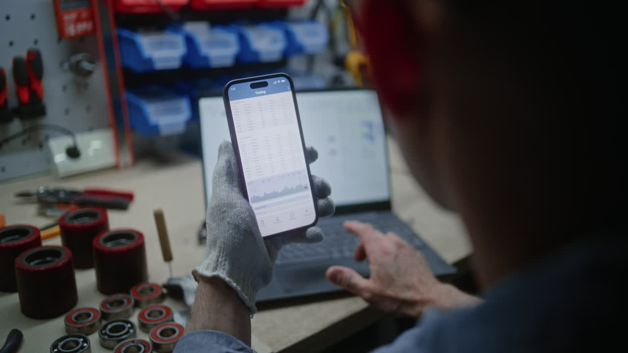 Man Checking Real-Time Stocks, Exchange Market Charts on Smartphone and Laptop. Employee Making Cryptocurrency Investments During Working Hours in Workshop, Combining Job with Online Trading. Close Up