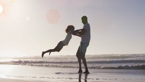 Animación-De-Manchas-Sobre-Un-Feliz-Padre-Afroamericano-Con-Su-Hija-En-Una-Playa-Soleada