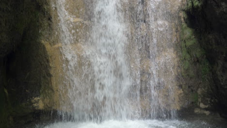 Nach-Unten-Kippende-Aufnahme-Eines-Tosenden-Wasserfalls-Im-Wald,-Der-In-Einen-Klaren-Teich-Fällt,-Zeitlupe