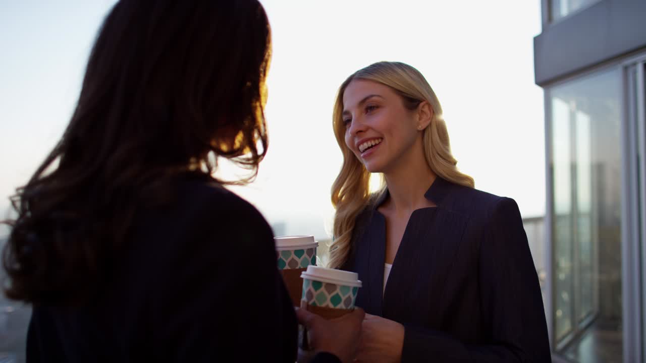 mujeres de negocios multiétnicas sonrientes disfrutando de café en el techo
