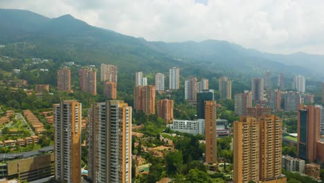 Drone-Descending-Above-El-Poblado-Neighborhood-on-Cloudy-Day-in-Medellin,-Colombia