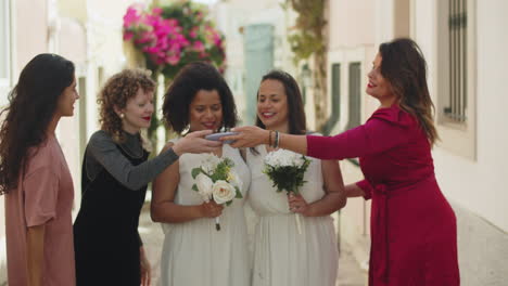 medium shot of lesbian brides taking photo with friends outdoors