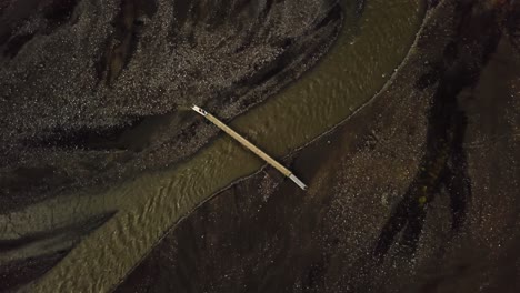 aerial drone view of people crossing a bridge, over a river flowing in the fimmvörðuháls area, iceland