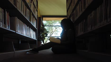 young black woman reads in a library - wide push in