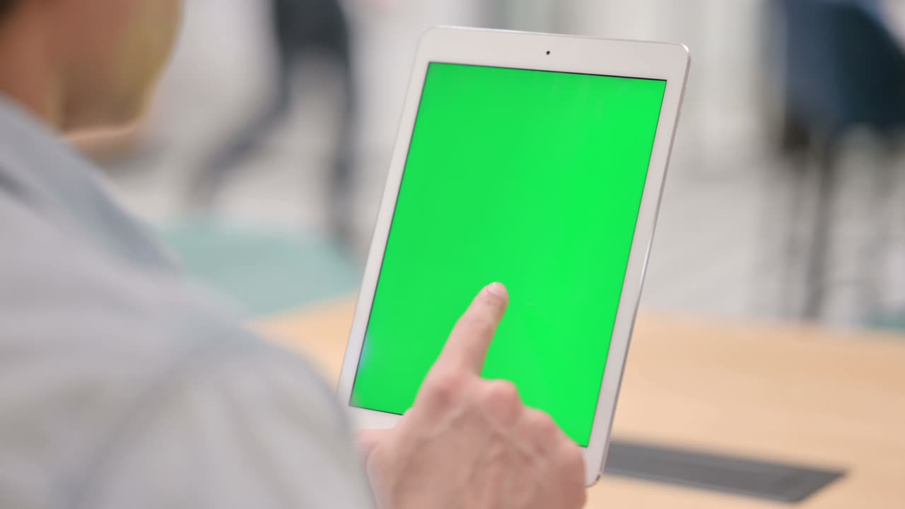 녹색 크로마 키 스크린을 가진 태블릿을 사용하는 남자