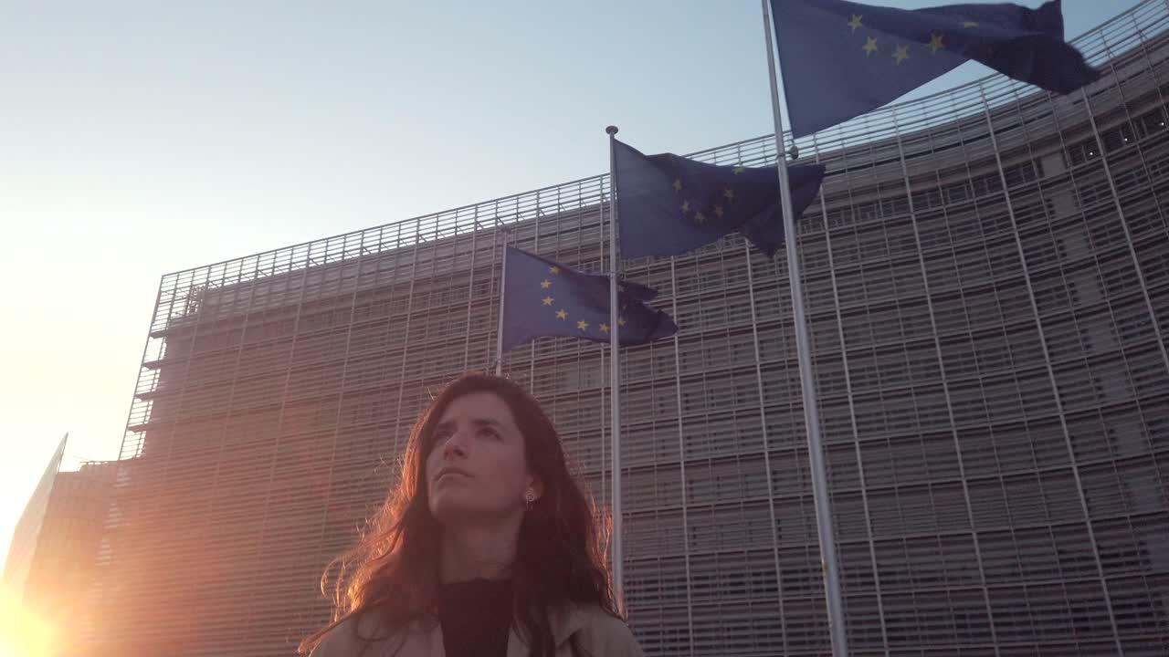 Woman looks up near EU flags at golden hour