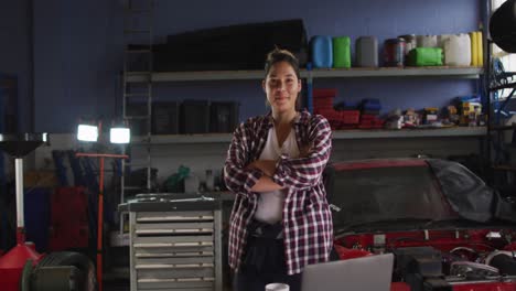 Portrait-of-female-mechanic-with-arms-crossed-smiling-at-a-car-service-station