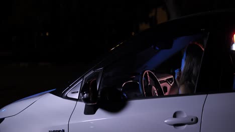 woman prepare for date doing makeup in parked car at night