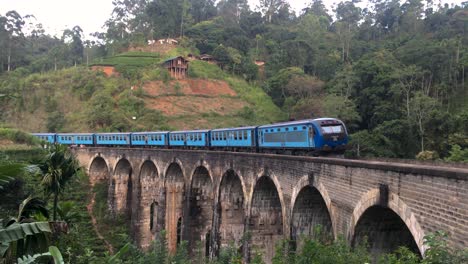 traditional blue train passing by nine arch bridge in demodara scenic travel destination.