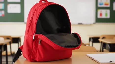 bright red backpack on a school desk in an empty classroom