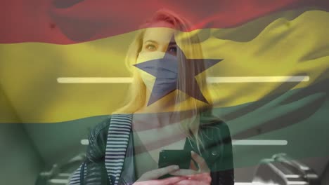 Animation-of-flag-of-ghana-waving-over-woman-wearing-face-mask-during-covid-19-pandemic