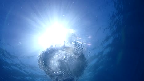 el sol visto desde debajo del agua con burbujas saliendo hacia el sol