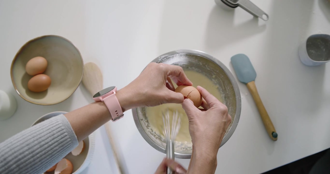 Tapping sieve rim, home cook is sifting flour, whisking eggs and pouring milk, making batter