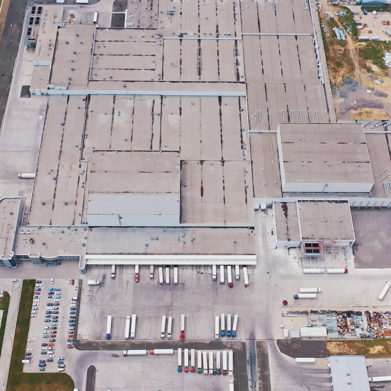 Aerial Shot of Industrial Warehouse/ Storage Building/ Loading Area where Many Trucks Are Loading/ Unloading Merchandise.