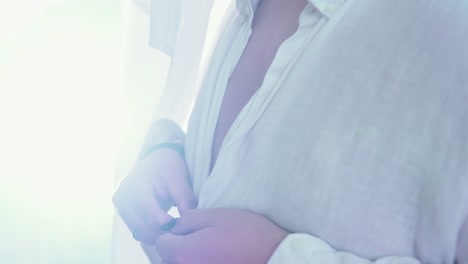 close-up of a lgtb homosexual man unbuttoning his shirt in slow motion with sunlight behind him