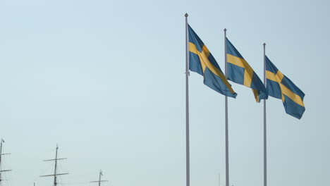 Vista-Estática-De-Tres-Banderas-Suecas-Moviéndose-En-El-Viento-Por-Mástiles-De-Veleros