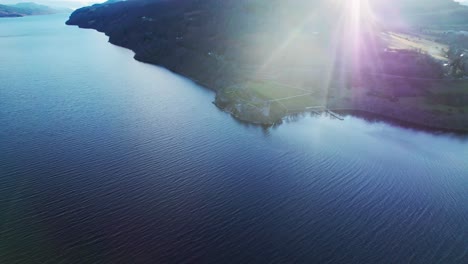 Urquhart-Castle-Aerial-drone-on-the-shores-of-Loch-Ness,-Scotland-on-a-sunny-day-between-highlands-mountains-establishing-shot