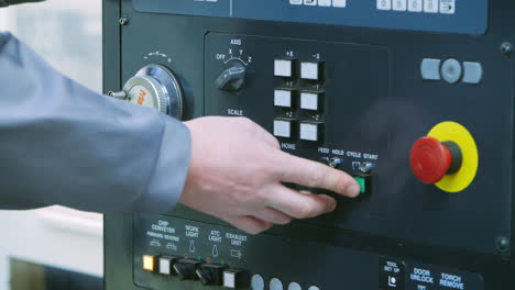 Engineer-starting-up-unit-by-pressing-buttons-on-control-panel