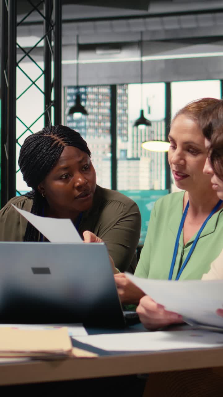 Vertical Video Businesswomen compare analytics and plan strategy in a modern workspace