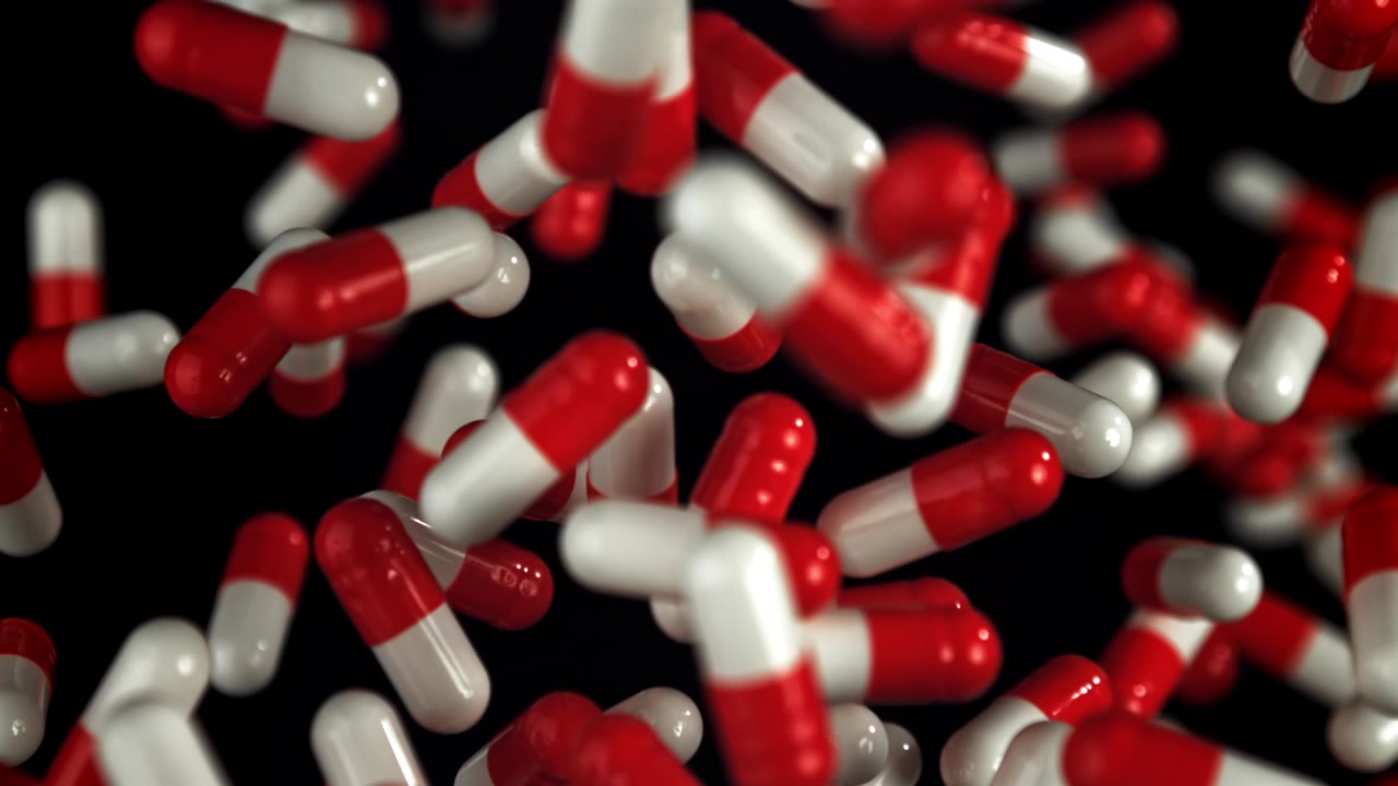 Primo piano di pillole mediche rosse e bianche che cadono al rallentatore