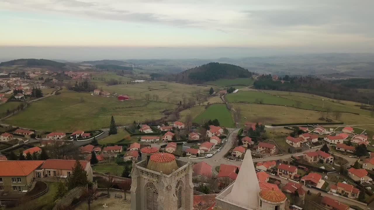drone disparado sobre la iglesia colegiada de saint bonnet le chateau revelando los montes du forez y la llanura du forez, departamento del loira cerca de saint etienne, francia