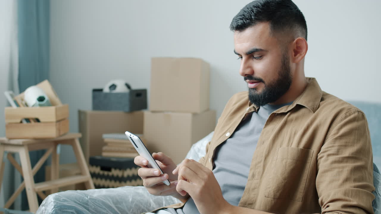 Man using a smartphone while moving into a new home
