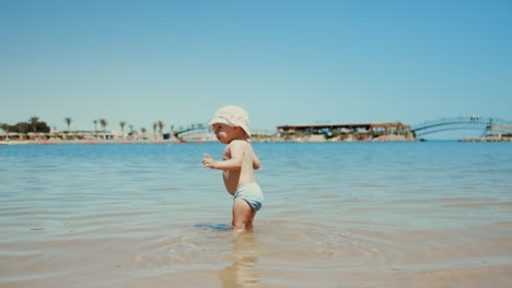 Kleiner-Junge-Blickt-An-Einem-Sonnigen-Tag-In-Die-Kamera.-Kleinkind-Bleibt-Im-Meerwasser.