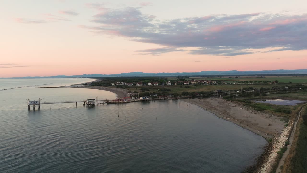 vista aérea de cabañas de pesca a orillas del estuario al atardecer, máquina de pesca italiana, llamada "trabucco", lido di dante, ravenna cerca del valle de comacchio