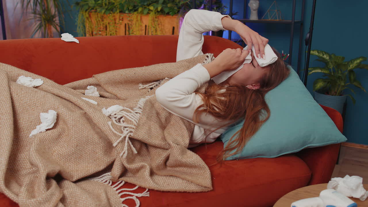 감기 나 알레르기 를  ⁇ 고 있는 아픈 여자 가 집 의 소파 에 누워 재채기 를 하고  ⁇ 데기 에  ⁇  을  ⁇ 는다