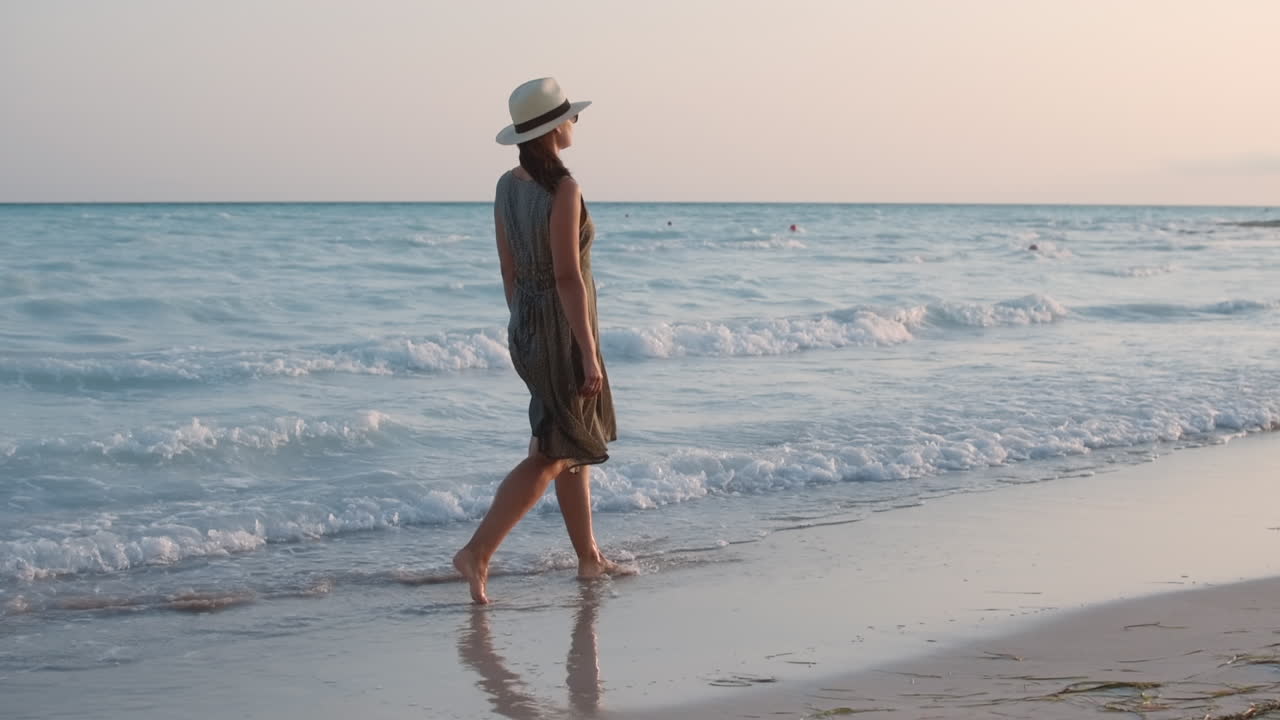 바 ⁇ 가에서 휴식을 취하는 예쁜 여성. 바다 파도에서 걸어다니는 맨발 여성 모델.