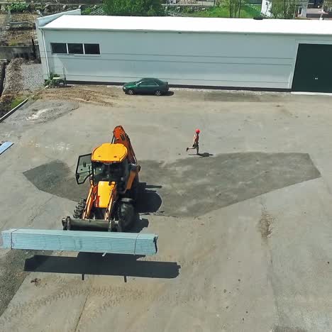 tractor working on the yard. industrial machine is carrying cargo on the background of the field on a solar plant construction. aerial view.